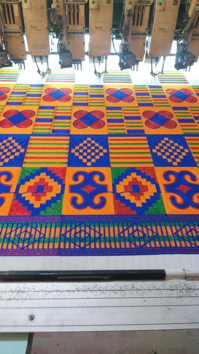 Multi-head embroidery machine stitching a kente-style design