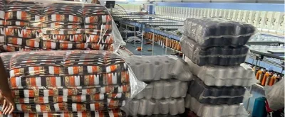 Kente fabric rolls and thread cones beside the embroidery floor